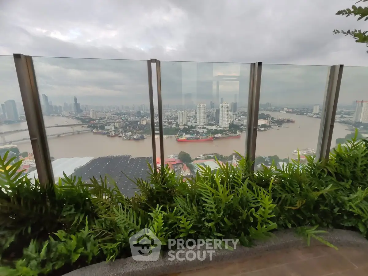 Stunning cityscape view from a high-rise balcony with lush greenery and river panorama.