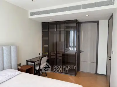 Modern bedroom with sleek glass wardrobe and cozy workspace