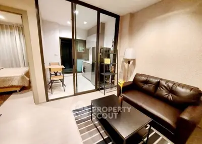 Modern living room with leather sofa and glass partition leading to kitchen
