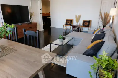 Spacious modern living room with stylish decor and large TV, perfect for relaxation and entertainment.