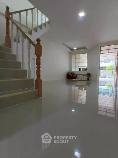 Spacious modern living room with glossy tiled floors and elegant staircase