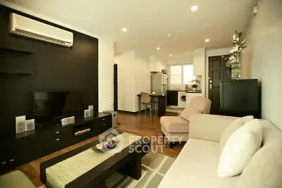 Modern living room with open kitchen, featuring stylish furniture and cozy ambiance.