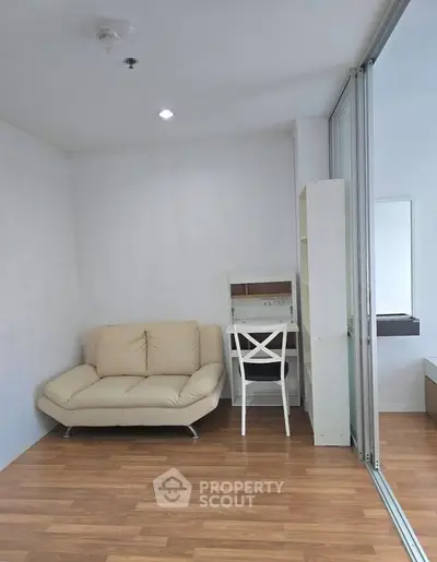 Modern living room with cozy sofa and study area, featuring sleek wooden flooring and bright lighting.
