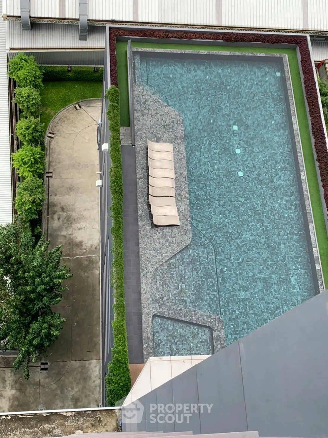 Stunning aerial view of modern rooftop pool with sleek design and lush greenery, perfect for luxury living.