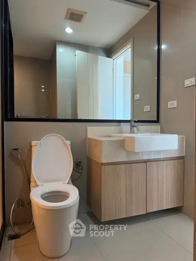 Modern bathroom with sleek fixtures and contemporary design, featuring a stylish vanity and toilet.