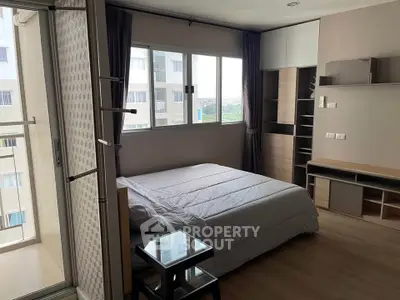 Modern bedroom with large window and balcony access in urban apartment