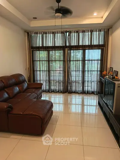 Spacious living room with leather sofa and large windows offering natural light.