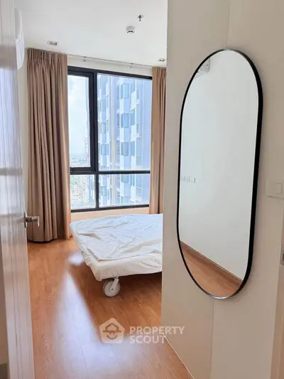Modern bedroom with large window and wooden flooring in high-rise apartment