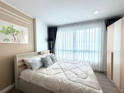 Modern bedroom with cozy decor and large window offering natural light