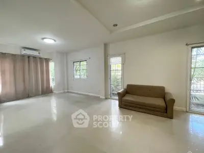 Spacious living room with large windows and natural light, featuring a cozy sofa and modern tile flooring.