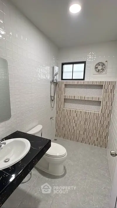 Modern bathroom with sleek black countertop and tiled shower area