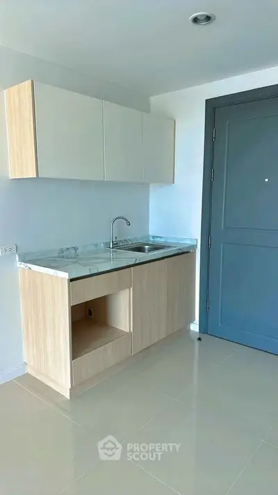 Modern minimalist kitchen with sleek cabinetry and marble countertop in a bright apartment.