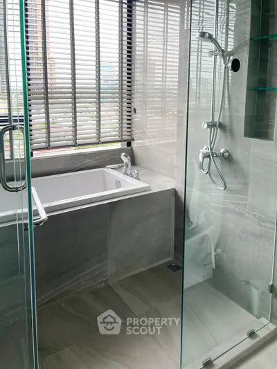 Luxurious bathroom with glass shower and bathtub, featuring modern fixtures and large windows.