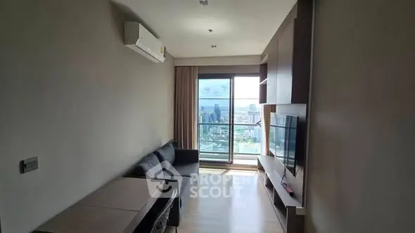 Modern living room with city view and balcony access, featuring sleek furniture and natural light.