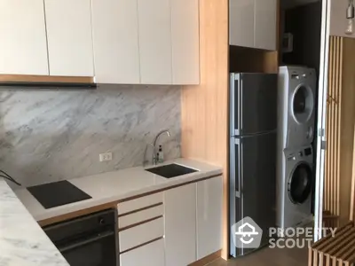 Modern kitchen with sleek cabinetry and stacked washer dryer unit