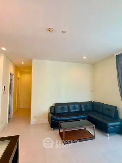 Spacious living room with modern leather sofa and sleek coffee table in a bright apartment.