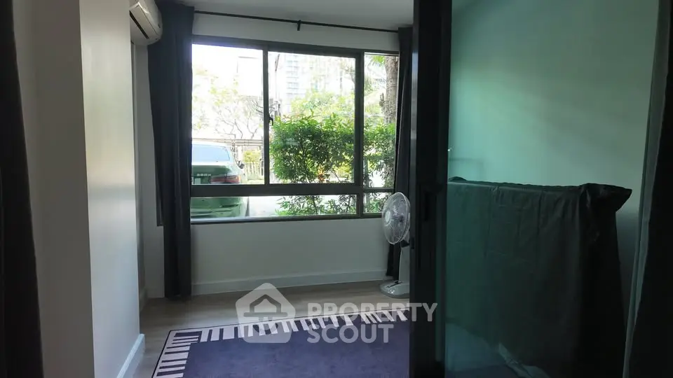 Cozy room with large window and garden view, featuring modern decor and natural light.