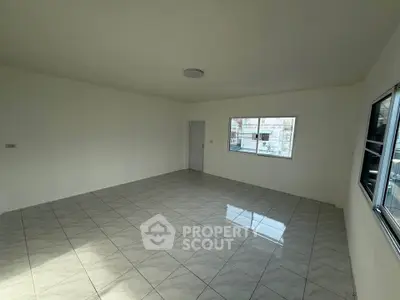 Spacious empty room with tiled flooring and large windows, perfect for customization.