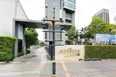 Modern condominium entrance with lush greenery and sleek architectural design.