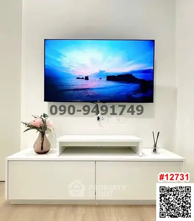 Modern living room with wall-mounted TV and sleek white furniture