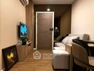 Cozy living room with modern decor and wooden flooring, featuring a comfortable sofa and wall-mounted TV.