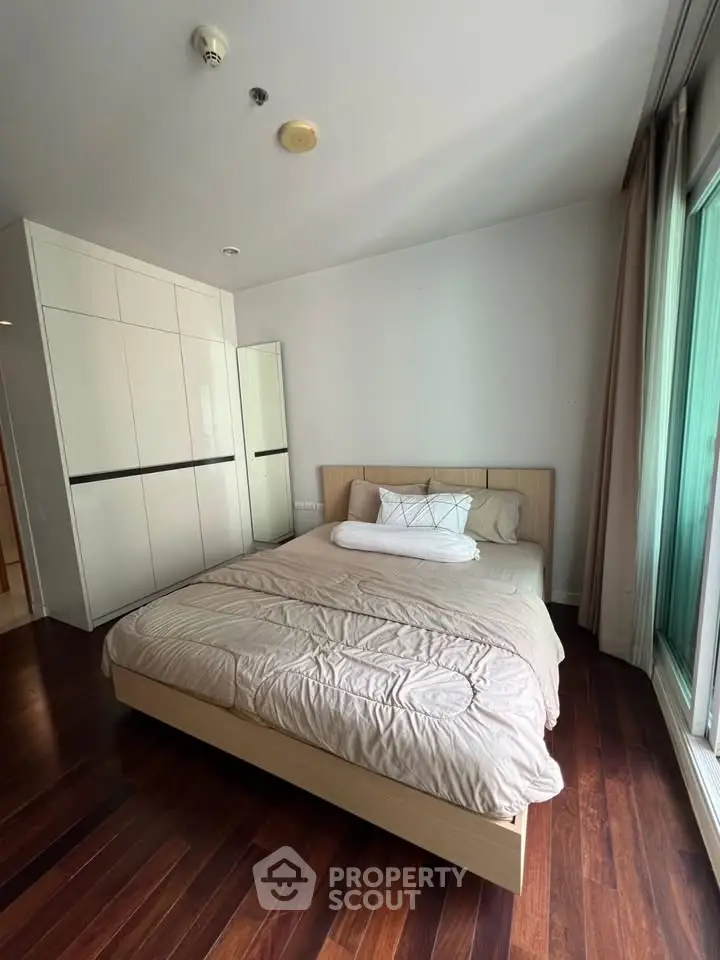 Cozy bedroom with wooden flooring and large wardrobe in modern apartment
