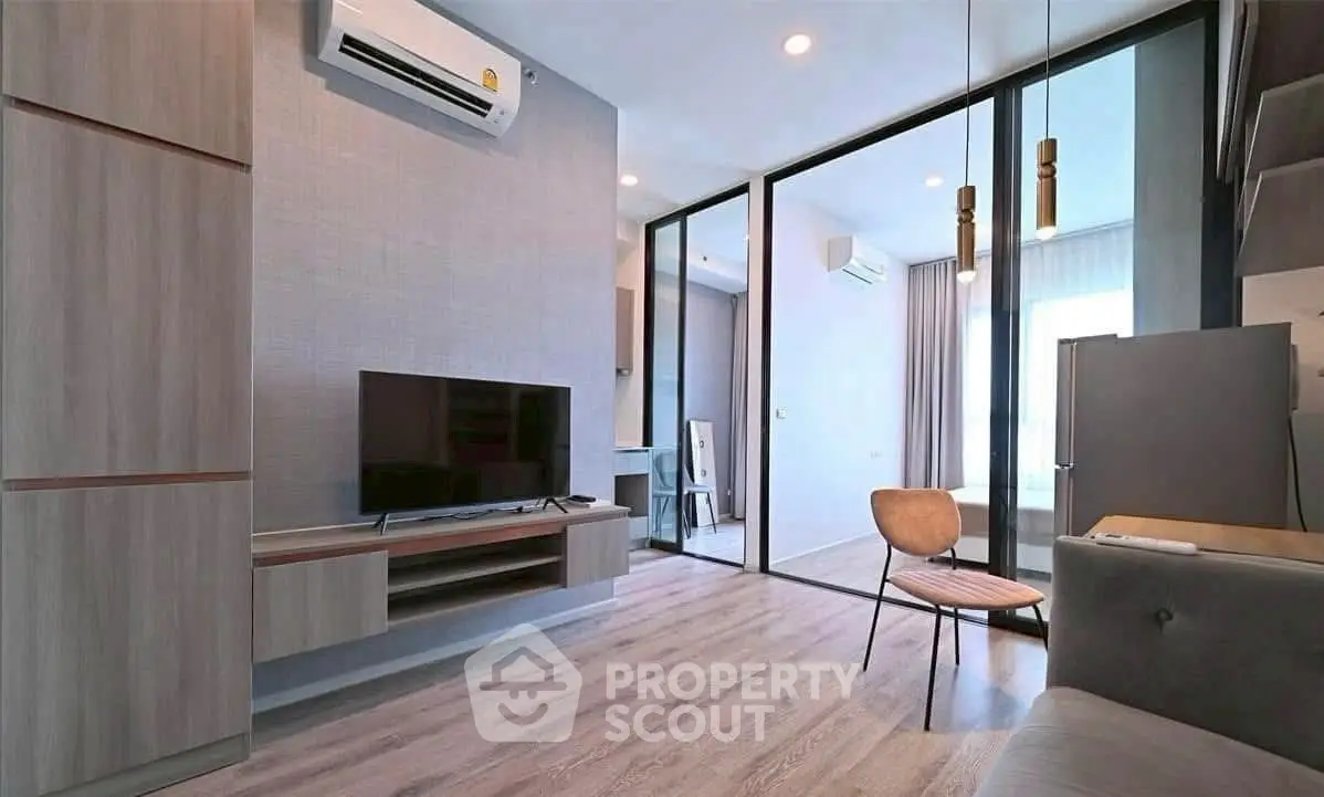 Modern living room with sleek design and natural light, featuring a TV and stylish furniture.