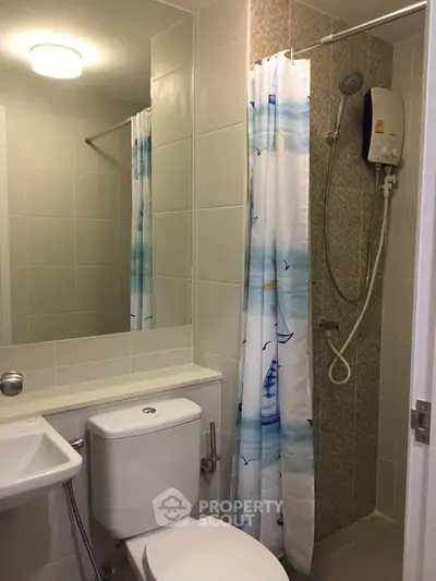 Modern bathroom with shower, toilet, and nautical-themed curtain in a cozy apartment.
