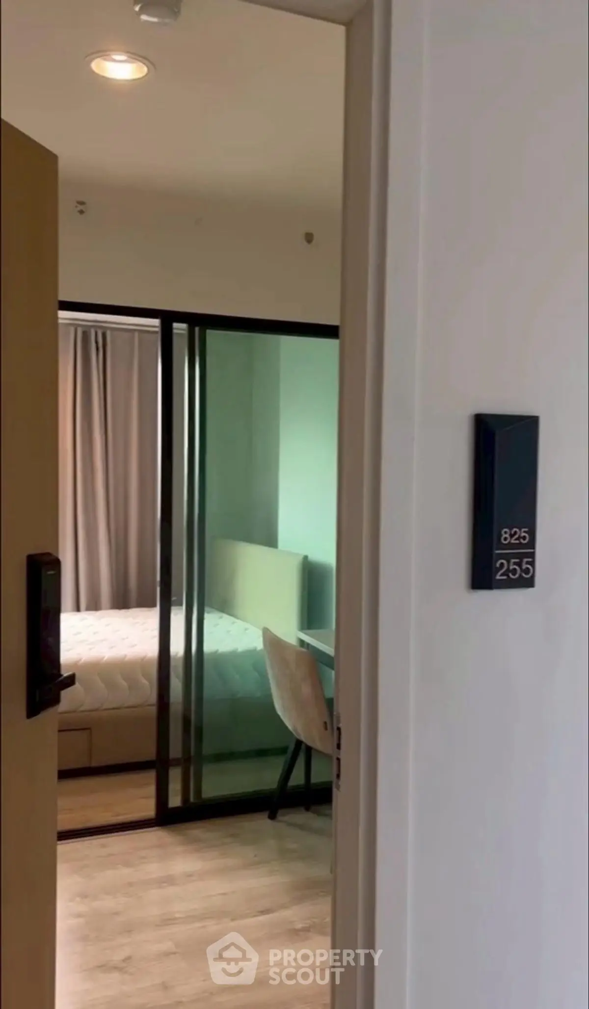 Modern apartment entrance leading to a cozy bedroom with sliding glass doors and stylish decor.