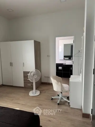 Modern bedroom with wardrobe, fan, and study desk in minimalist design.