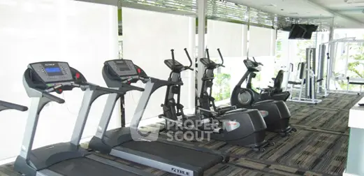Modern gym with state-of-the-art fitness equipment and large windows for natural light.