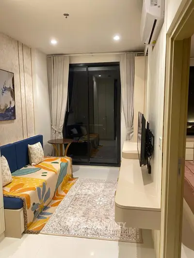 Cozy living room with modern decor and balcony access, featuring stylish furniture and ambient lighting.