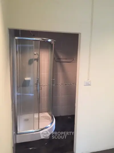 Modern bathroom with sleek glass shower enclosure and tiled walls.