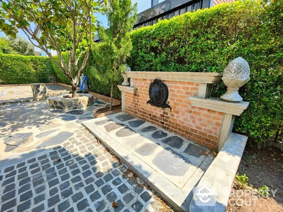 Charming garden area with brick fountain and lush greenery, perfect for outdoor relaxation.