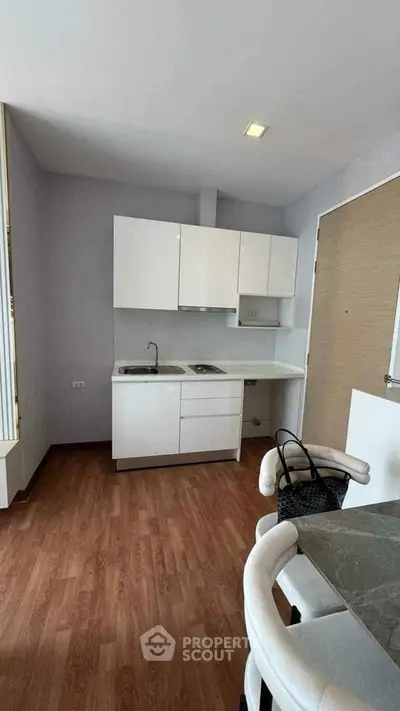Modern compact kitchen with sleek white cabinets and wooden flooring