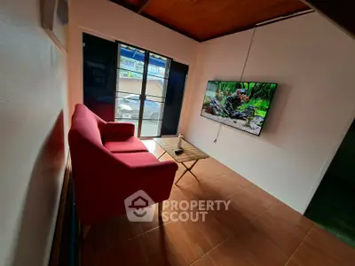 Cozy living room with red sofa and wall-mounted TV, featuring natural light and modern decor.