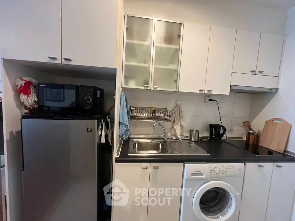 Compact kitchen with modern appliances including washing machine and microwave, ideal for urban living.