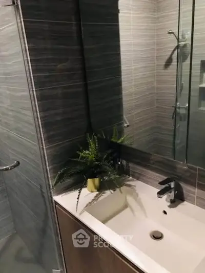 Modern bathroom with sleek design and stylish fixtures, featuring a glass shower and elegant sink.