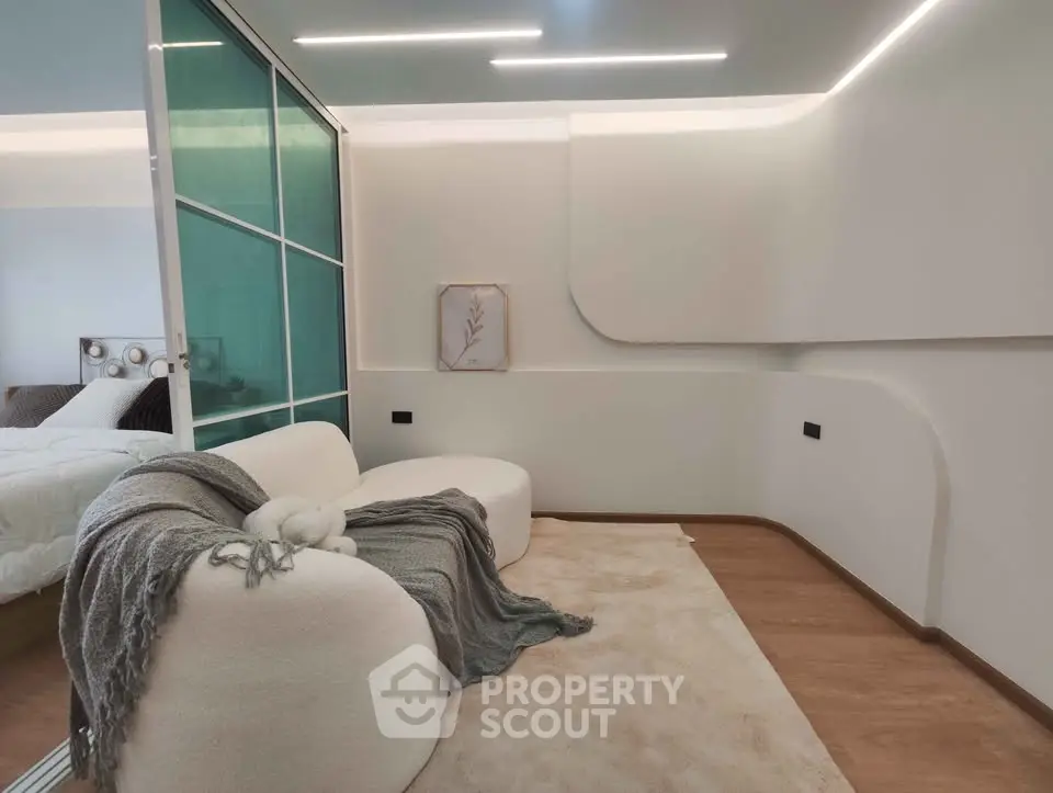 Modern bedroom with stylish decor and cozy seating area, featuring elegant lighting and contemporary design.