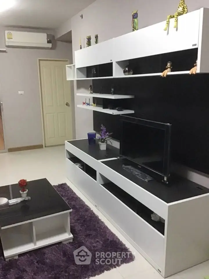 Modern living room with sleek black and white furniture and vibrant purple rug