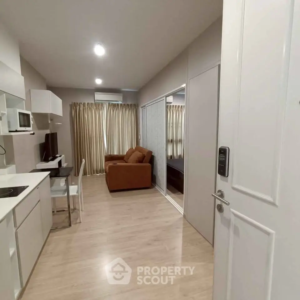 Modern apartment interior with open kitchen and cozy living area featuring a brown sofa and stylish decor.