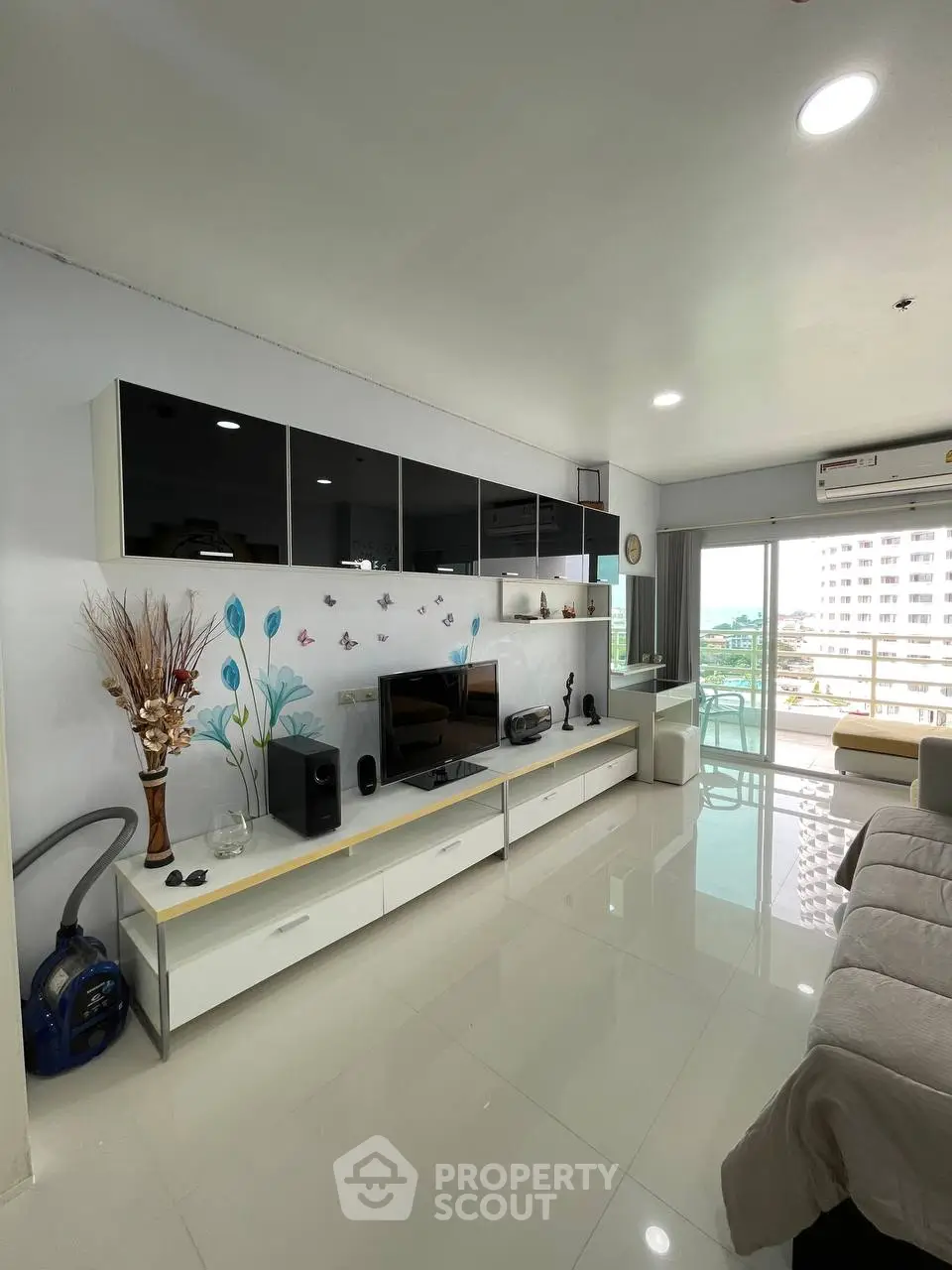 Modern living room with sleek entertainment unit and large windows offering city views.