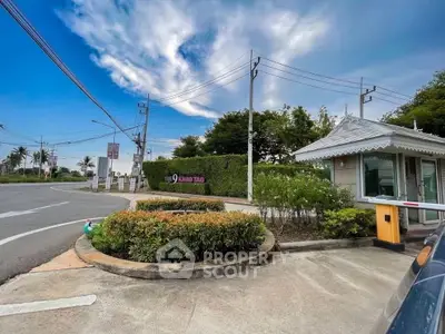 Charming gated entrance with lush greenery and clear blue skies, perfect for serene living.