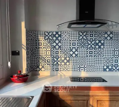 Modern kitchen with stylish patterned backsplash and sleek cooktop