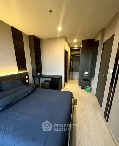 Modern bedroom with sleek design and ambient lighting, featuring a cozy bed and functional workspace.