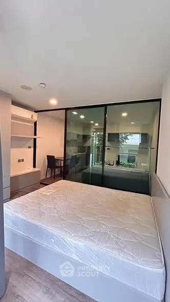 Modern bedroom with large window and built-in storage, offering a serene view.