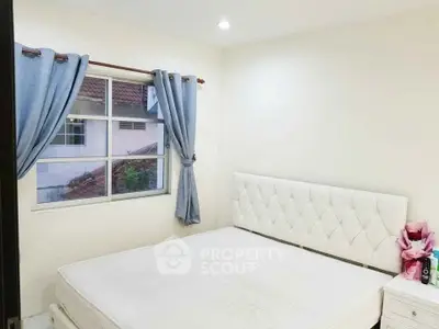 Cozy bedroom with white tufted headboard and window view, perfect for relaxation.
