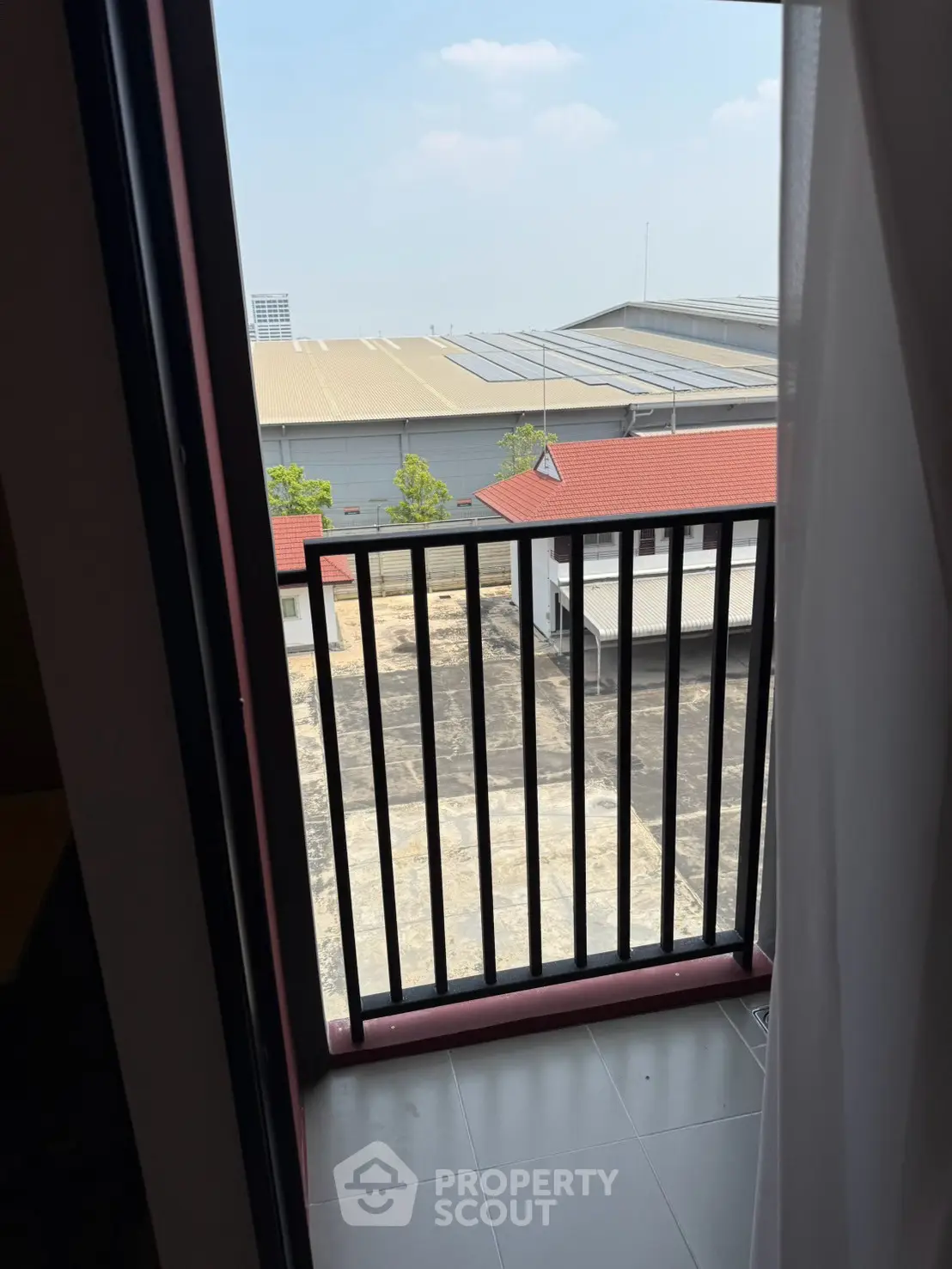 Charming balcony view with industrial backdrop, perfect for urban living enthusiasts.