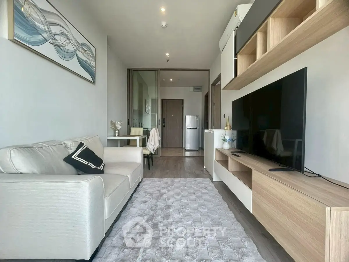 Modern living room with sleek design and open layout, featuring a cozy sofa and large TV.