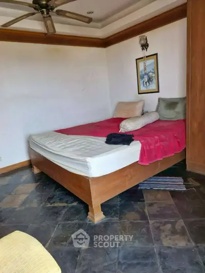 Cozy bedroom with wooden bed frame and slate flooring, featuring a ceiling fan and wall art.